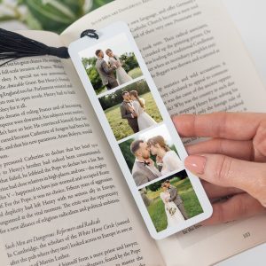 A high-quality, ultra-glossy aluminium bookmark with a black tassel, featuring four personalised custom photos of a couple on their wedding day. The bookmark is shown holding a page in an open book, serving as a unique and sentimental keepsake, perfect for a wedding, anniversary, or birthday gift.