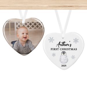 Heart-shaped ceramic Christmas bauble personalised with baby photo on one side and penguin with snowflakes, name, and year on the other side, baby’s first Christmas keepsake ornament with ribbon, unique personalised photo decoration gift for new parents, grandparents, or family, perfect festive tree ornament.