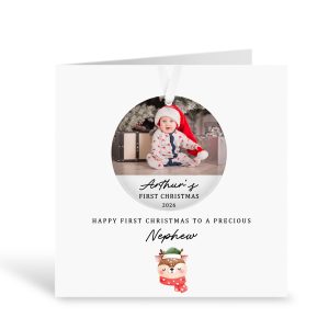 Personalised first Christmas nephew card featuring a removable acrylic bauble decoration with a baby photo wearing a Santa hat. Custom card reads “Arthur’s First Christmas 2026” and “Happy First Christmas to a Precious Nephew”. Handmade luxury 300gsm greeting card with a cute festive reindeer design and white ribbon for hanging the bauble. Perfect keepsake Christmas gift for a baby nephew.